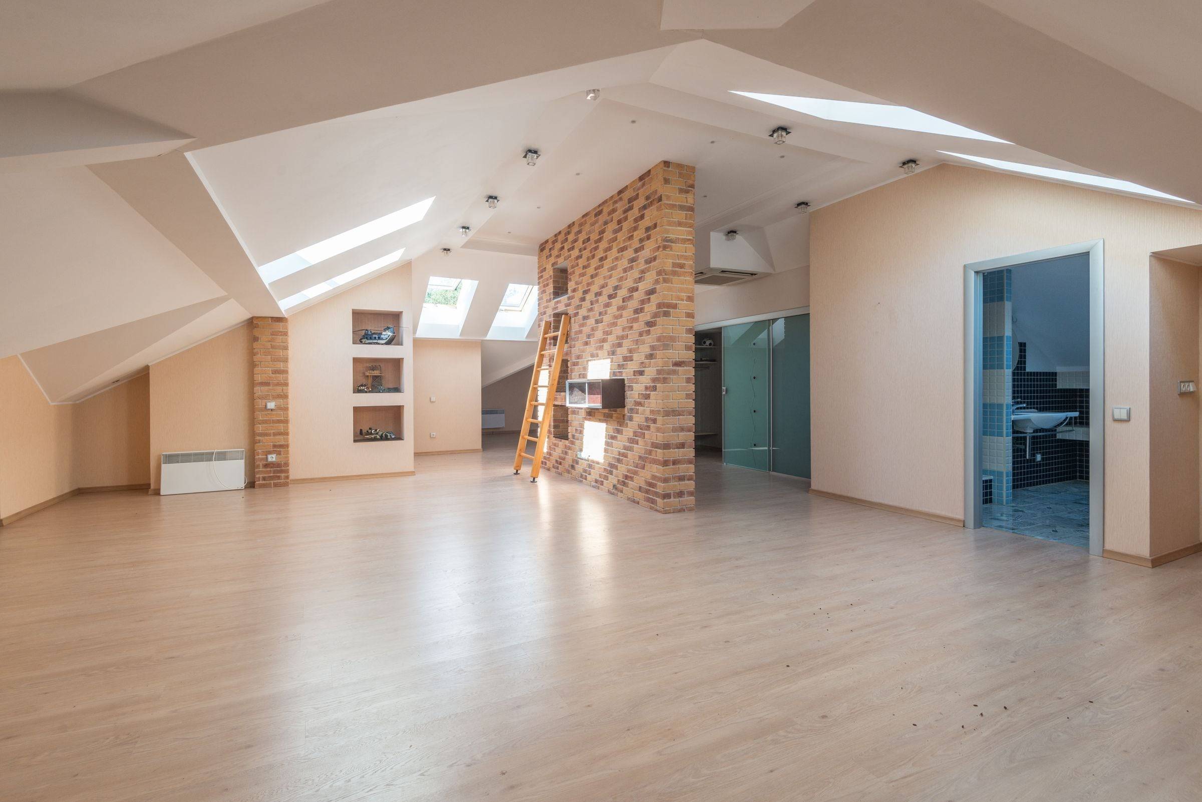 Combles vides sous de grands velux, murs en pente nus et sol en parquet clair.