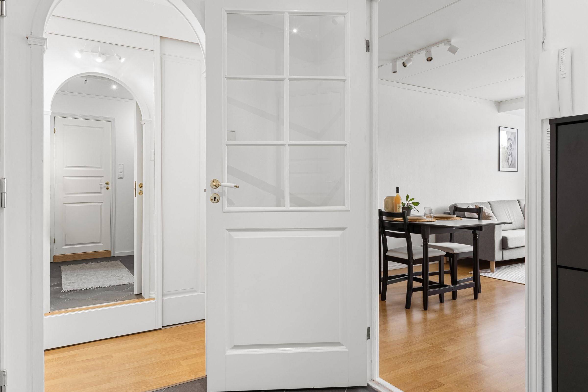 Portes intérieures blanches à panneaux, l’une vitrée et ouverte sur un séjour lumineux.